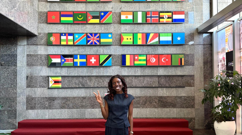 Mastercard Foundation Scholar Kaitochukwu standing in front of flags in AfDB foyer