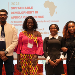 Mastercard Foundation Scholar Favour Peters with conference team on stage