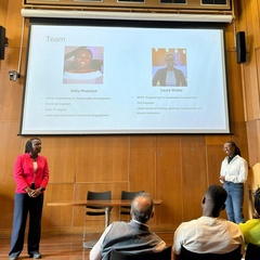 Two female students making a presentation, with their presentation projected on the screen in the background.